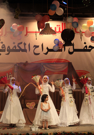 Palestinian children, dressed in bride clothes, sing during a collective wedding party which involved 80 grooms and brides in Gaza city on August 2, 2009.