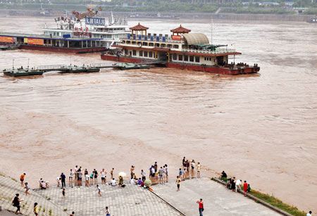 Local residents stand close to a wharf as the flood water of this year&apos;s highest level in the Yangtze River flows past southwest China&apos;s Chongqing Municipality, on August 3, 2009. Emergency departments of the local authority are keeping high alert as some places were submerged.