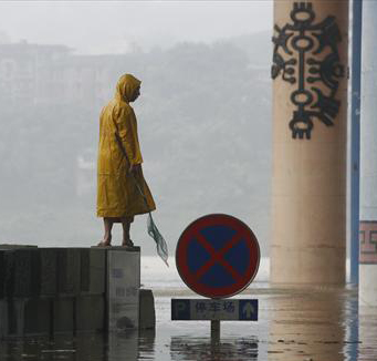 A man stands near a parking lot flooded after a rainstorm in Ciqikou town of Chongqing in southwest China, on August 3, 2009. In the next 10 days, the heat weave will continue in most parts of south China while rainstorms will hit the northeast, said Chen Zhenlin, a spokesman for the China Meteorological Administration (CDA). 