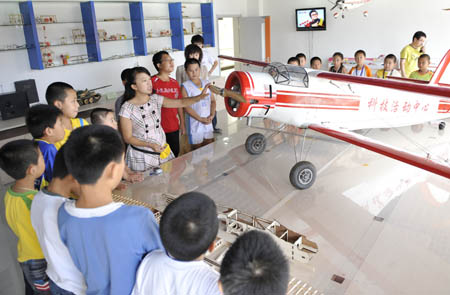 Pupils learn the flying theory of plane at the Children's Science Palace in Qingshan District, Baotou City, north China's Inner Mongolia Autonomous Region, on August 2, 2009. 