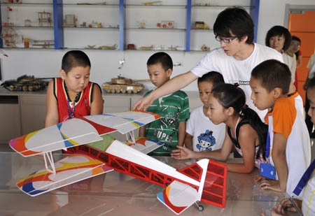 Pupils learn from a teacher to make a model plane at the Children's Science Palace in Qingshan District, Baotou City, north China's Inner Mongolia Autonomous Region, on August 2, 2009. 