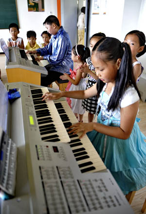 Pupils learn electronic piano at the Children's Science Palace in Qingshan District, Baotou City, north China's Inner Mongolia Autonomous Region, on August 2, 2009.