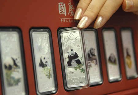 A salesgirl shows a colorful silver bullion with the design of a giant panda, in Beijing, capital of China, on August 4, 2009. This set of ornaments including six silver bullions with the design of giant pandas on them will be on the market on August 5 to celebrate the upcoming National Day. 