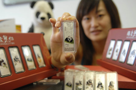 A salesgirl shows a colorful silver bullion with the design of a giant panda, in Beijing, capital of China, on August 4, 2009. 