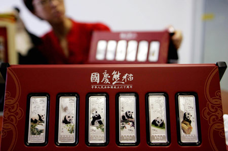 A staff member shows a set of colorful silver bullions in Beijing, capital of China, on August 4, 2009.