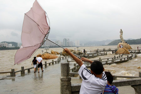A Chinese tourist manages to hold his umbrella against strong wind on a trestle bridge on the beach near Zhuhai city in south China's Guangdong Province, on August 4, 2009 as the tropical storm of 'Goni' approaches to the city.