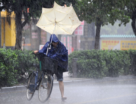  A local struggles in the rain in Guangzhou, capital of south China's Guangdong Province, on Aug. 5, 2009. The tropical storm Goni landed at a speed of 83 km per hour early Wednesday morning in Taishan of Guangdong Province, according to local meteorological station. Meteorologists also said another tropical storm, Morakot, which formed on the west Pacific Ocean Tuesday morning, was now moving at 20 km per hour northwestward. (Xinhua/Lu Hanxin)