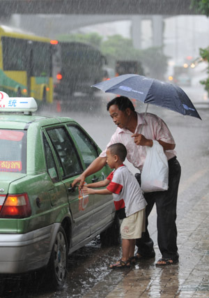  Locals get into a taxi in Guangzhou, capital of south China's Guangdong Province, on Aug. 5, 2009. The tropical storm Goni landed at a speed of 83 km per hour early Wednesday morning in Taishan of Guangdong Province, according to local meteorological station. Meteorologists also said another tropical storm, Morakot, which formed on the west Pacific Ocean Tuesday morning, was now moving at 20 km per hour northwestward. (Xinhua/Lu Hanxin)