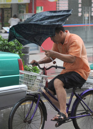 A local struggles in the rain in Guangzhou, capital of south China's Guangdong Province, on Aug. 5, 2009. The tropical storm Goni landed at a speed of 83 km per hour early Wednesday morning in Taishan of Guangdong Province, according to local meteorological station. Meteorologists also said another tropical storm, Morakot, which formed on the west Pacific Ocean Tuesday morning, was now moving at 20 km per hour northwestward. (Xinhua/Lu Hanxin)