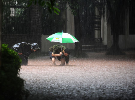 People stand on flooded street in China's Chongqing Municipality, on August 4, 2009. Heavy rain hit Chongqing on Tuesday causing traffic jam and the closure of highways. A total of 379,900 people are plagued by the strong rainfalls.