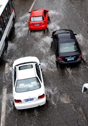 Three cars run on a flooded street in China's Chongqing Municipality, on August 4, 2009. Heavy rain hit Chongqing on Tuesday causing traffic jam and the closure of highways. A total of 379,900 people are plagued by the strong rainfalls. 