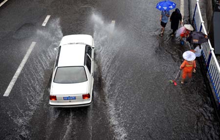 A car runs on a flooded street in China's Chongqing Municipality, on August 4, 2009. Heavy rain hit Chongqing on Tuesday causing traffic jam and the closure of highways. A total of 379,900 people are plagued by the strong rainfalls. 