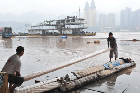 The workers of a logistics company move stock from the floodwaters in southwest China's Chongqing Municipality, on August 4, 2009. The continual heavy rainfalls in Chongqing brought about flood over the city, with many lower sections of the riverside streets submerged. 