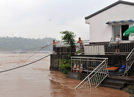 A man nets fish at home as the swollen river reaches the yard in southwest China's Chongqing Municipality, on August 4, 2009. The continual heavy rainfalls in Chongqing brought about flood over the city, with many lower sections of the riverside streets submerged. 