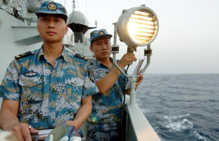 Chinese navy soldiers aboard the Zhoushan missile frigate say hello via light signal to Saudi Arab's Abha missile frigate on the Gulf of Aden, on August 4, 2009. Two frigates and a supply ship from the Chinese navy is on their escort mission to fend off Somali pirates.