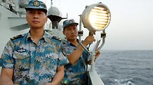 Chinese navy soldiers aboard the Zhoushan missile frigate say hello via light signal to Saudi Arab's Abha missile frigate on the Gulf of Aden, on August 4, 2009. Two frigates and a supply ship from the Chinese navy is on their escort mission to fend off Somali pirates.