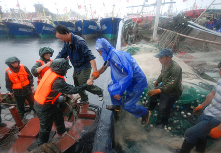 Soldiers help fishermen go to safe zone in the rain in Taizhou City, east China's Zhejiang Province, on August 6, 2009.