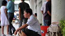 A passenger sits at the port of Haikou, capital of south China's Hainan Province, on August 7, 2009. Navigation has resumed across the Qiongzhou Strait which separates Hainan from the Chinese mainland. A large number of passengers and tourists stranded on the island by the storm were still waiting for home.