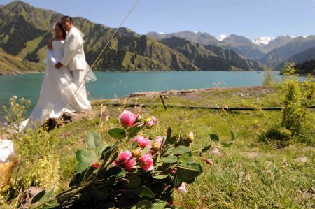 A new couple pose for wedding photos at the Tianchi Lake in the Tianshan Mountains of northwest China&apos;s Xinjiang Uygur Autonomous Region, on August 8, 2009.