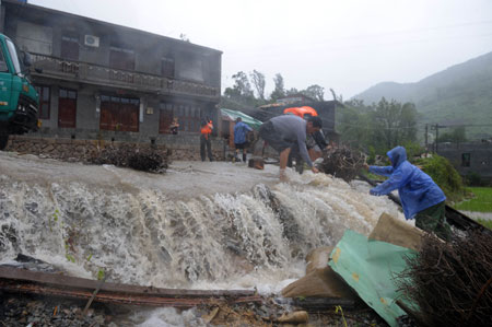 Armed policemen help villagers to evacuate materials at Hongshan Village in Xiapu County, southeast China's Fujian Province, on August 9, 2009.