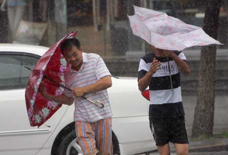 People walk against strong wind in heavy rain on a street in Wenzhou, east China&apos;s Zhejiang Province, on August 9, 2009. 