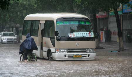 A resident rides bike on a flooded street in Wenling, east China&apos;s Zhejiang Province, on August 9, 2009. 