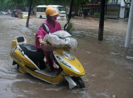 A man pushes the motorbike on a flooded street in Wenling, east China&apos;s Zhejiang Province, on August 9, 2009.