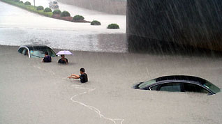 Rescuers pull a car out of water in rain in Wenzhou, east China's Zhejiang Province, on August 9, 2009. Typhoon 'Morakot' slammed into Chinese provinces on the eastern coast on Sunday, causing casualties, destroying houses and inundating farmlands