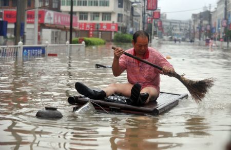 A man wade through the flooded street by home-made raft in Cangnan, east China's Zhejiang Province, on August 10, 2009. 