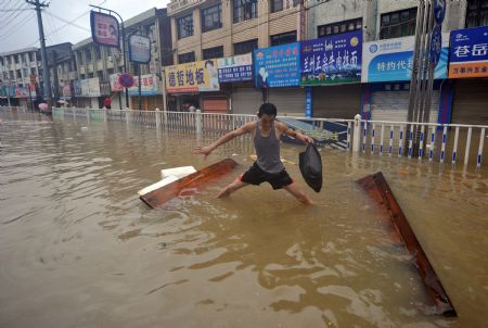 A man tries to stand after his raft fell apart in the flooded street in Cangnan, east China's Zhejiang Province, on August 10, 2009.