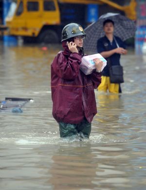 A rescuer makes a phone call in the flooded street in Cangnan, east China's Zhejiang Province, on August 10, 2009. 