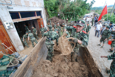 Armed policemen help clear roads and houses after a landslide caused by Typhoon Morakot at Kewan Village of Fuding, southeast China's Fujian Province, on August 10, 2009. The local government organized the people in the typhoon-stricken area to rebuild their homes on monday right after the Typhoon faded away. 