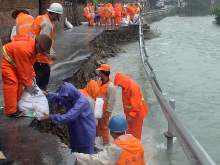 Rescue workers place sandbags for the highway roadbed destroyed by Typhoon Morakot in Taizhou, east China&apos;s Zhejiang Province, on August 10, 2009. The local government organized the people in the typhoon-stricken area to rebuild their homes on monday right after the Typhoon faded away.