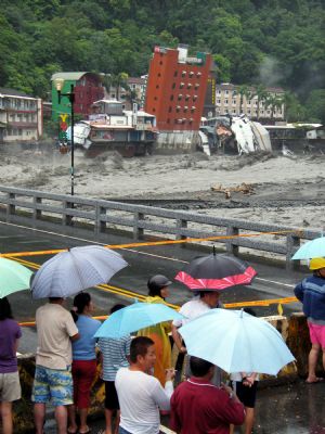 People gathered to watch that a hotel building leans before falling in a heavily flooded river after Typhoon Morakot hit eastern Taiwan, on Sunday, on August 9, 2009. 