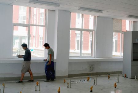 Two workers make the final touch of the interior construction of a classroon of Tianjin High Middle School in Lueyang, northwest China&apos;s Shaanxi province, on August 12, 2009