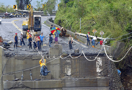 Rescue workers move past a ruined bridge by temporary steel ropes for relief work on the road to Xinkai village in Kaohsiung of Taiwan, on August 12, 2009. The village was hit by debris flow caused by typhoon Morakot, which might result in serious casualties. 