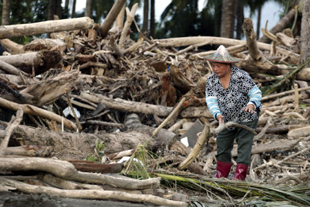 A farmer moves away the wood brought by flood from her field in Kaohsiung, southeast China's Taiwan Province, Aug. 14, 2009. 