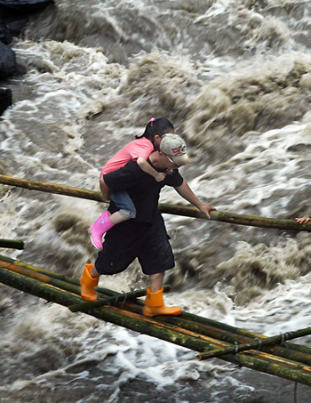 A villager moves across a makeshift bamboo bridge over floodwater in Hsinfa Village of Luikuei Township, Kaohsiung, southeast China's Taiwan Province, on August 15, 2009. 