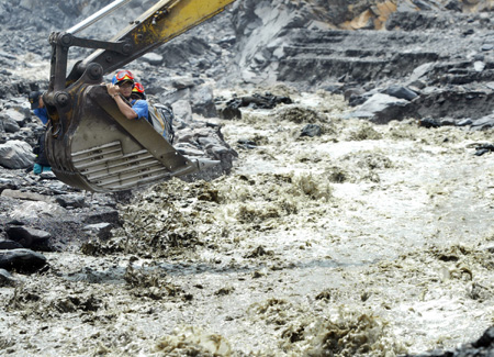 Villagers cross over floodwater by a crane grab in Hsinfa Village of Luikuei Township, Kaohsiung, southeast China's Taiwan Province, on August 15, 2009. 