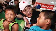 Chinese actor Jet Li (C) sings a song with children at a shelter in Chishan Town of Kaohsiung in southeast China's Taiwan, on August 15, 2009.