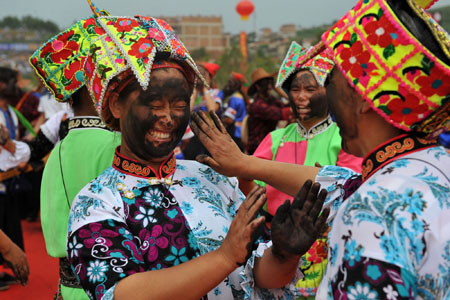 People daub black wood ash on each other on the Painted-face Festival held in Qiubei County of southwest China's Yunnan Province, on August 15, 2009. The Painted-face Festival, or the Hualian Festival, was a traditional festival of the Yi ethnic group in Qiubei County, where people used to daub their faces black to drive away evil in ancient age. [