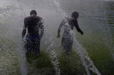 Children seek relief from a heat wave in the fountains near the Eiffel Tower in Paris, capital of France, on August 19, 2009. Seven provinces in France are under a heatwave alert on Wednesday with temperature in Paris climbed to 35 degrees Celsius.