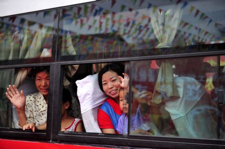 Residents of the Guanmenyan Village in Danjiangkou City, central China's Hubei Province, say goodbye to their neighbors from a bus window when they are about to leave their former residence for a new location on August 20, 2009.