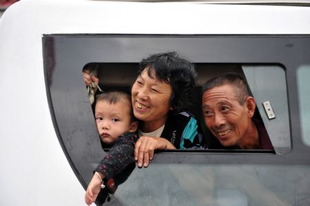 Residents of the Guanmenyan Village in Danjiangkou City, central China's Hubei Province, say goodbye to their neighbors from a bus window when they are about to leave their former residence for a new location on August 20, 2009.