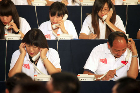 Volleyball coach Lang Ping (L, front) and Sun Haiping (R, front), head coach of China's Olympic and world champion Liu Xiang, work as operators for donation during a television fundraiser in Beijing, capital of China, on August 20, 2009. 