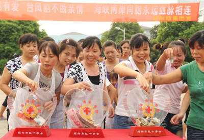 Workers of a Shaoxing garment company make their donation in cash for the Taiwan typhoon victims, in east China's Zhejiang Province, on August 20, 2009. 