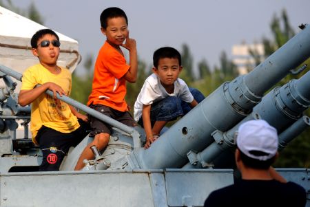 Children play on a gunboat displaying at the Weapon Square in Baotou of north China's Inner Mongolia Autonomous Region, on August 19, 2009.