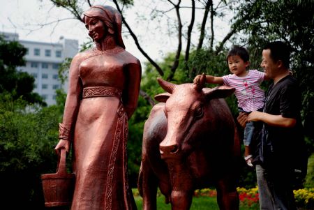 A father helps his daughter to touch the sculpture at the Friendship Square in Baotou of north China's Inner Mongolia Autonomous Region, on August 21, 2009.