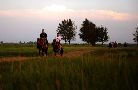 Visitors ride horses at an ecological park in Baotou of north China's Inner Mongolia Autonomous Region, on August 21, 2009.