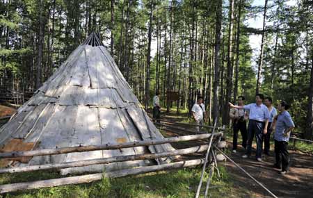 Tourists view a bark house used to be home of Owenke ethnic group in Genhe City of north China's Inner Mongolia Autonomous Region, on Aug. 16, 2009.
